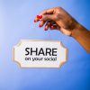 Close-up of a hand holding a 'Share on your social' sign on a vibrant blue backdrop.